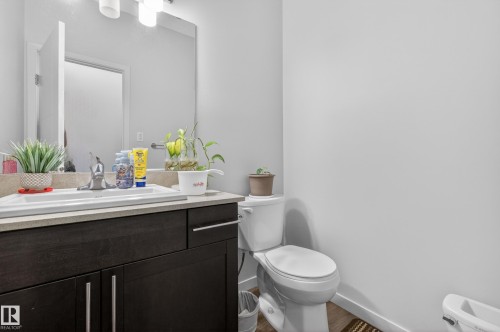 Bathroom featuring a dark wood-finish vanity with chrome hardware, an integrated sink, and light countertop - 1404 25 Avenue, Edmonton, AB 