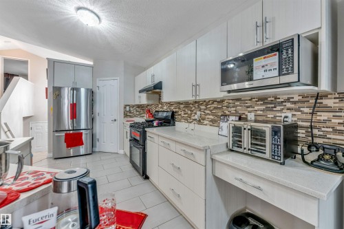 Contemporary kitchen with light-toned cabinetry, light countertops, and a mosaic tile backsplash - 3519 22 Street Nw, Edmonton, AB 