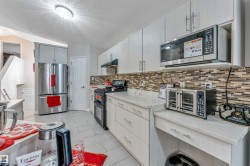 Contemporary kitchen with light-toned cabinetry, light countertops, and a mosaic tile backsplash - 