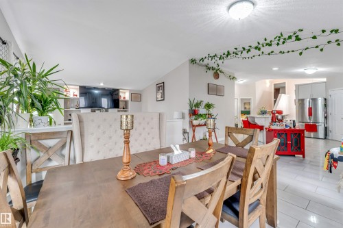 Dining area featuring a wood-finish table, upholstered high-back bench seating, and X-back chairs - 3519 22 Street Nw, Edmonton, AB 