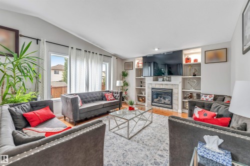 Living area featuring light wood-finish flooring and a stone-surround fireplace - 3519 22 Street Nw, Edmonton, AB 