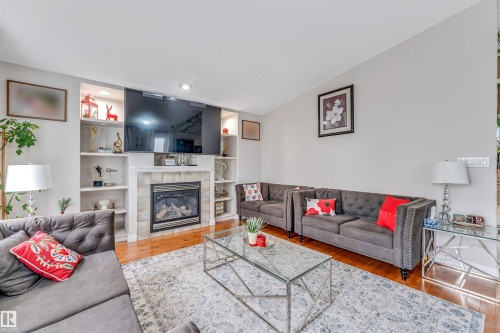 Living area featuring a gas fireplace with a tiled surround, built-in shelving, hardwood flooring, and recessed lighting - 3519 22 Street Nw, Edmonton, AB 