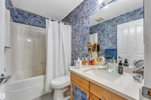 Bathroom featuring a white bathtub, toilet, and a vanity with a light-colored countertop - 3519 22 Street Nw, Edmonton, AB 