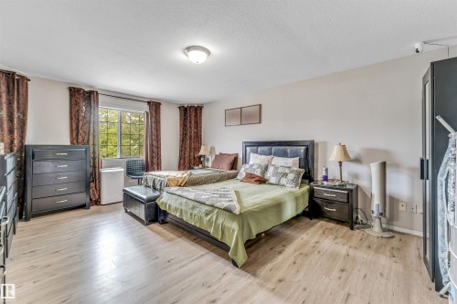Spacious room featuring wood-finish flooring, a window with natural light, and ample wall space - 3519 22 Street Nw, Edmonton, AB 