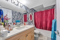Bathroom featuring a vanity with wood-finish cabinetry, a light-toned countertop, and an undermount sink - 
