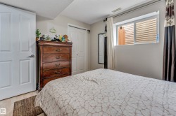 Bedroom featuring a window with blinds, wood-finish flooring, two panel doors, and a built-in closet with bi-fold doors - 
