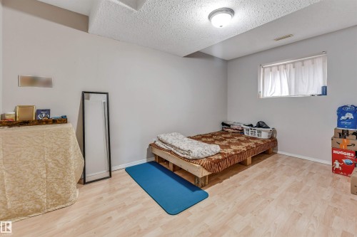 Bright room featuring light wood-finish flooring, a white textured ceiling, and neutral-toned walls - 3519 22 Street Nw, Edmonton, AB 