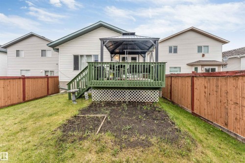 Rear exterior featuring a green-painted deck with white lattice skirting, a gazebo, and a sloped lawn - 3519 22 Street Nw, Edmonton, AB 