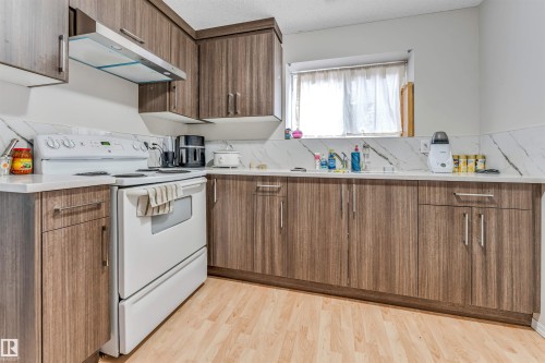 Kitchen featuring wood-finish cabinetry, white countertops, and a white tile backsplash - 3519 22 Street Nw, Edmonton, AB 