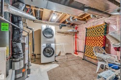 Dedicated utility area featuring a stacked washer and dryer unit, exposed ceiling joists, and visible ductwork - 