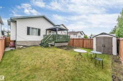 Spacious backyard featuring a sloped lawn and a fenced perimeter - 