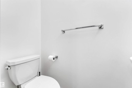 White wall finishes complemented by a contemporary white toilet and chrome fixtures, including a towel bar and toilet paper holder - 45 2710 66 Street, Edmonton, AB 
