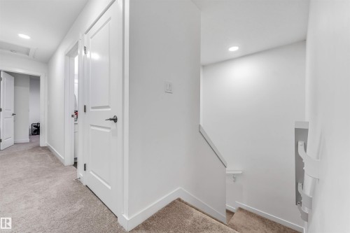 Upper-level hallway featuring neutral carpeting, recessed lighting, white interior doors, and crisp white trim - 45 2710 66 Street, Edmonton, AB 