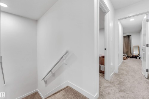 Carpeted staircase featuring a light gray handrail - 45 2710 66 Street, Edmonton, AB 