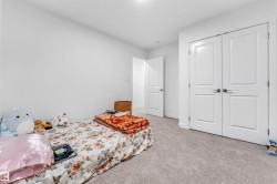 Bedroom featuring light-colored wall-to-wall carpeting, white painted walls, and a white paneled door - 
