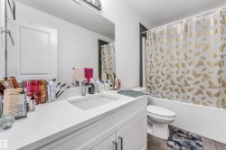 Bathroom featuring a white vanity with integrated sink, a rectangular mirror, and a bathtub with shower - 
