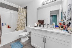 Bathroom featuring a white vanity with integrated sink, a rectangular mirror, and an overhead vanity light fixture - 