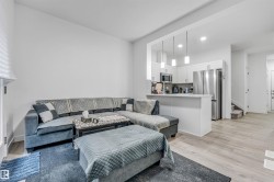 Open-concept living area featuring light wood-finish flooring, white walls, and recessed lighting - 