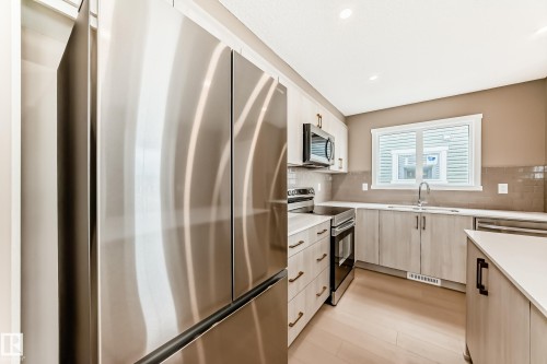 Contemporary kitchen featuring stainless steel appliances, light wood-finish cabinetry, white countertops, and a subway tile backsplash - 1210 Stoneside Road, Sherwood Park, AB - Indoor Photo Showing Kitchen With Upgraded Kitchen