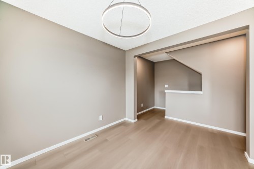 Open concept room featuring wood-finish flooring, neutral-toned walls, white trim, and a contemporary circular pendant light fixture - 1210 Stoneside Road, Sherwood Park, AB - Indoor Photo Showing Other Room