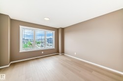 Bright interior space featuring a large three-panel window, light wood-finish flooring, neutral-toned walls, white trim, and a ceiling-mounted flush light fixture - 