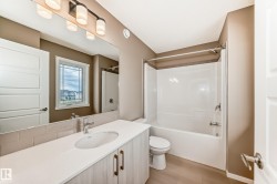 Contemporary bathroom featuring a light-toned vanity with a single basin, a white countertop, and a subway tile backsplash - 