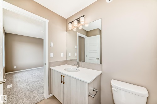 Bathroom featuring a single vanity with a white countertop, undermount sink, and a three-light fixture above the mirror - 1210 Stoneside Road, Sherwood Park, AB - Indoor Photo Showing Bathroom