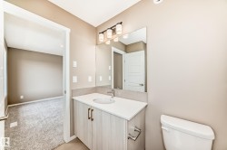 Bathroom featuring a single vanity with a white countertop, undermount sink, and a three-light fixture above the mirror - 