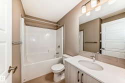 Bathroom featuring a vanity with a white countertop, an undermount sink, and wood-finish cabinetry - 