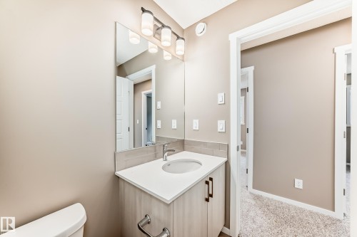 Bathroom vanity featuring a light wood-finish cabinet with dark hardware, an undermount sink, and a white countertop - 1210 Stoneside Road, Sherwood Park, AB - Indoor Photo Showing Bathroom