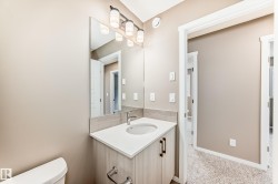 Bathroom vanity featuring a light wood-finish cabinet with dark hardware, an undermount sink, and a white countertop - 