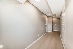 Hallway with light wood-finish flooring, neutral-toned walls, recessed lighting, and white panel doors - 