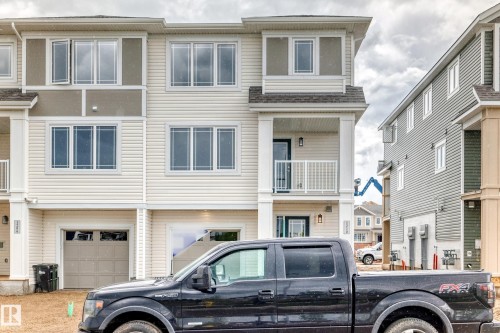 Cream-colored multi-story building featuring white trim and a covered balcony with a white railing - 1210 Stoneside Road, Sherwood Park, AB - Outdoor With Balcony With Facade