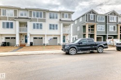 Modern townhome exteriors featuring light-colored siding, multiple windows, attached garages, and a front entrance balcony - 