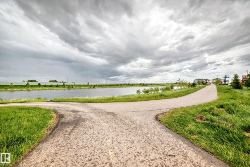 Paved pathway bordering a body of water with established landscaping - 1210 Stoneside Road, Sherwood Park, AB - Outdoor With View