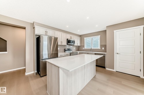 Contemporary kitchen featuring light wood-finish cabinetry, stainless steel appliances, a white countertop island, and wood-finish flooring - 1210 Stoneside Road, Sherwood Park, AB - Indoor Photo Showing Kitchen With Upgraded Kitchen