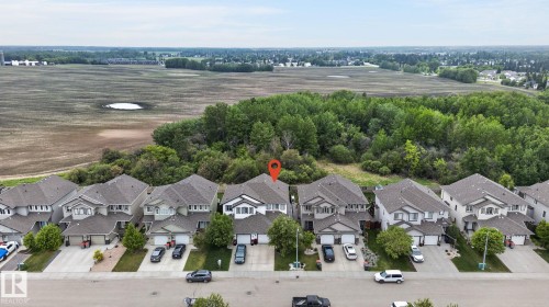 Residential property featuring a light-colored exterior, an attached garage, and a grey shingle roof - 64 South Creek Wynd, Stony Plain, AB 