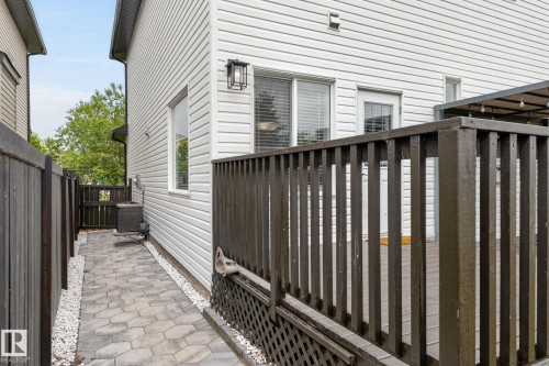 Paver walkway with white stone accents leading to a private outdoor space featuring a brown wooden deck with matching privacy fencing - 64 South Creek Wynd, Stony Plain, AB 