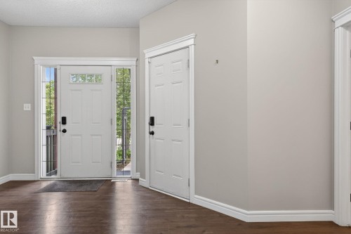 Entryway featuring wood-finish flooring, a white paneled door with transom and sidelight windows, and a second white paneled door - 64 South Creek Wynd, Stony Plain, AB 