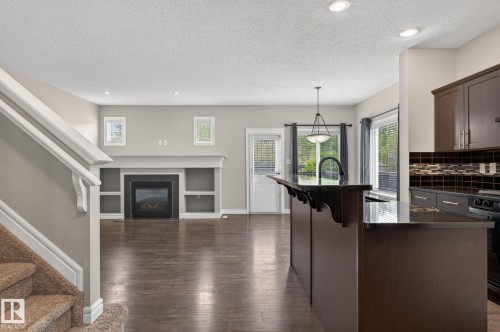 Open-concept living area with dark wood-finish flooring - 64 South Creek Wynd, Stony Plain, AB 