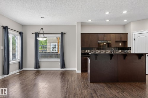 Kitchen island featuring dark wood cabinetry, a dark countertop, and a built-in sink - 64 South Creek Wynd, Stony Plain, AB 