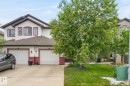 Two-story residence featuring white siding with burgundy trim accents, a two-car garage, and a concrete driveway - 64 South Creek Wynd, Stony Plain, AB 