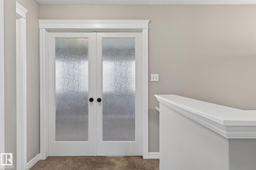 Double French doors with frosted glass panels and matte black hardware - 64 South Creek Wynd, Stony Plain, AB 