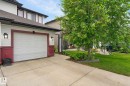 Attached single-car garage with panel door, concrete driveway, and exterior lighting fixtures - 64 South Creek Wynd, Stony Plain, AB 