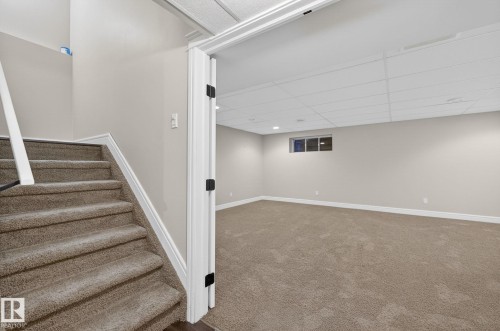 Lower-level room featuring neutral-toned carpet, light grey walls, and a drop ceiling with recessed lighting - 64 South Creek Wynd, Stony Plain, AB 