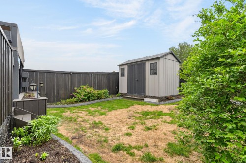 Backyard featuring a privacy fence and a storage shed with double doors and a window - 64 South Creek Wynd, Stony Plain, AB 