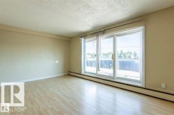 Spacious room featuring light wood-finish flooring, neutral wall tones, and a large sliding glass door - 