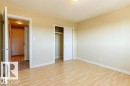 Spacious room featuring wood-finish flooring, light-toned walls, and a built-in closet with sliding doors - 307 8215 83 Avenue, Edmonton, AB 