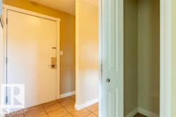 Entryway featuring a white door with brass hardware, ceramic tile flooring, and a recessed storage area with a bi-fold door - 