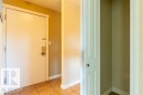 Entryway featuring a white door with brass hardware, ceramic tile flooring, and a recessed storage area with a bi-fold door - 307 8215 83 Avenue, Edmonton, AB 